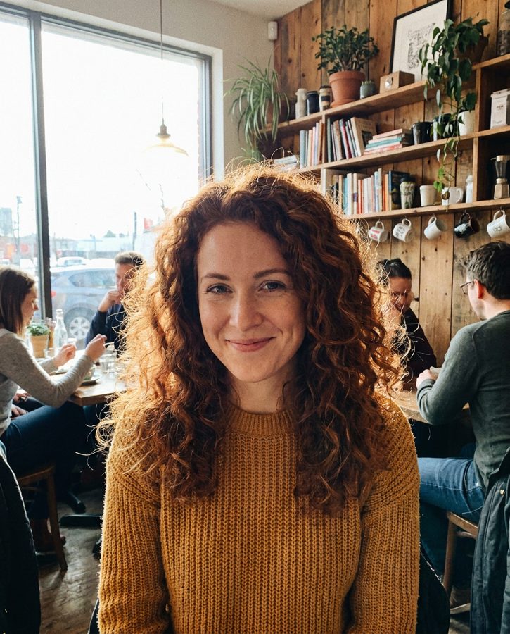 Woman with curly auburn hair in a busy café